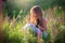 A girl sits in a blooming field with a beautiful tricolor kitten. Blooming sage