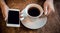 Girl sits in a cafe and holds a cup of tea and a phone in her hands, waiting for a call