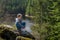 A girl sits on a cliff and looks at nature, girl sitting on a rock and enjoying valley view.