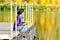 Girl sits on a dock near the water in a hat and with leaves in her hands. Sunny day