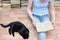 Girl sits on the floor and reads a book next to a black cat lying. Close-up