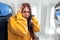 A girl sits in front of an airplane window and is nervous, afraid to fly, the cabin of a passenger airliner. Aerophobia, phobia,