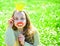 Girl sits on grass at grassplot, green background. Child posing with cardboard smiling lips and crown for photo session