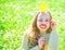 Girl sits on grass at grassplot, green background. Child posing with cardboard smiling lips and crown for photo session