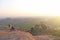 A girl sits with her back on the top of the mountain and looks at the sunset at Hampi and welcomes the sun. Meditation, harmony,