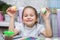 The girl sits in kitchen and holds the Easter eggs painted with watercolor paints in hand