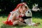 a girl sits on the lawn with a toy panda and kisses him on the nose