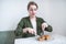 Girl sits in a light restaurant and eats a sandwich with a knife and fork. The woman is having breakfast at the cafe