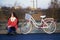 The girl sits next to a parked bike. Rest on the spring cycle