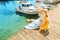 Girl sits on the pier near the parked boats on the Mediterranean coast. Vacation and travel concept