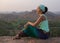 The girl sits on a rock and admires the stony scenery at sunset