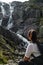 The girl sits on a rock and looks towards the waterfall Wielka Siklawa