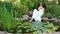 Girl sits on the shore of a pond