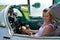 Girl sits and smiles in cabin of old jet fighter MiG-21 holding the control stick