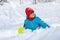 A girl sits in a snowdrift and looks funny at the top of the slide