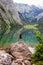A girl sits on a stone on a large lake Obersee in the Alps