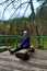 The girl sits on a wooden pier on a forest lake. Peace and tranquility