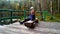 The girl sits on a wooden pier on a forest lake. Peace and tranquility