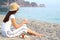 Girl sitting on the beach holds a paper cup and a plate of apples