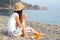 Girl sitting on the beach holds a paper cup and a plate of food