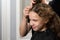 Girl sitting in beauty salon and smiling, stylist working on her hairdo