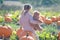 Girl sitting on a big pumpkin hugging teddy bear