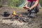 Girl sitting while camping near the fire heated and drink hot tea