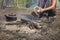 Girl sitting while camping near the fire heated and drink hot tea