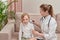 The girl is sitting on the couch. Doctor checks child hearing with an otoscope.