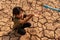 A girl sitting on dry ground. Water crisis, Concept hope and drought