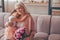 Girl sitting on the grandmothers laps holding bouquet of flowers at home