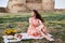 A girl sitting on the grass at a picnic with basket with sunflowers