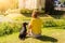 Girl sitting with her little black dog in a park in front of a medieval castle on sunset