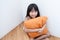 Girl sitting hugging pillow orange.