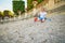 Girl sitting on a large heap of stones and playing with pebbles