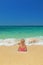 Girl sitting in the ocean breaking waves on the sand beach