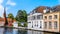 Girl sitting in an open window with a modern mobile phone in a historic brick house in the medieval city of Bruges, Belgium