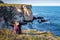 Girl sitting at a picturesque rocky coastline