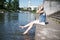 Girl sitting at the pier and hanging bare feet