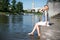 Girl sitting at the pier and hanging bare feet