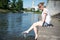 Girl sitting at the pier and hanging bare feet