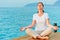 Girl sitting on a pier in lotus position