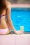 Girl sitting at poolside with beer glass