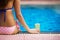 Girl sitting at poolside with beer glass