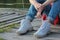 Girl sitting on a river beach on a wooden pier. Closeup of teenage legs in modern and trendy white sneakers and rolled up jeans. W