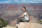 girl sitting on the rock of the cliff in front of the impressive landscape of the grand canyon