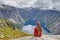 Girl sitting on rock and looking at Norwegian mountain landscape. Trail to Trolltunga rock. Ringedalsvatnet lake, Norway