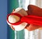 Girl sitting on sandy beach in the sun adjusting hat. Blue sky, blue sea red scarf. Spain.