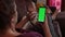 A girl sitting on the sofa typing on the smartphone with a green screen