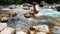 Girl sitting on the stone mountain rivers, hand leads them through the water enjoying the freshness